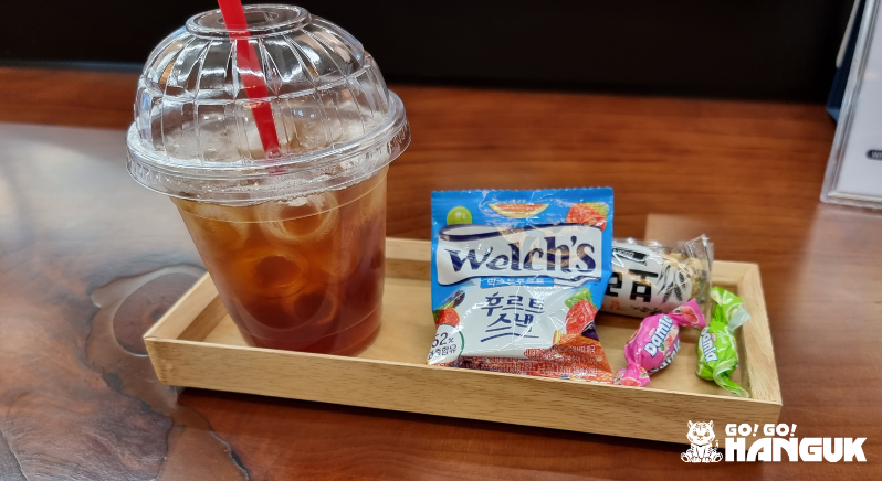 Iced Americano coffee with some Korean candies on a table