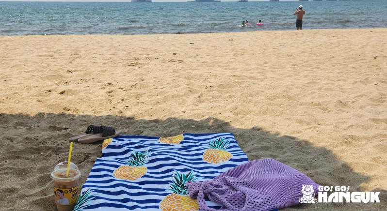 Beach towel, bag and an iced coffee on the beach