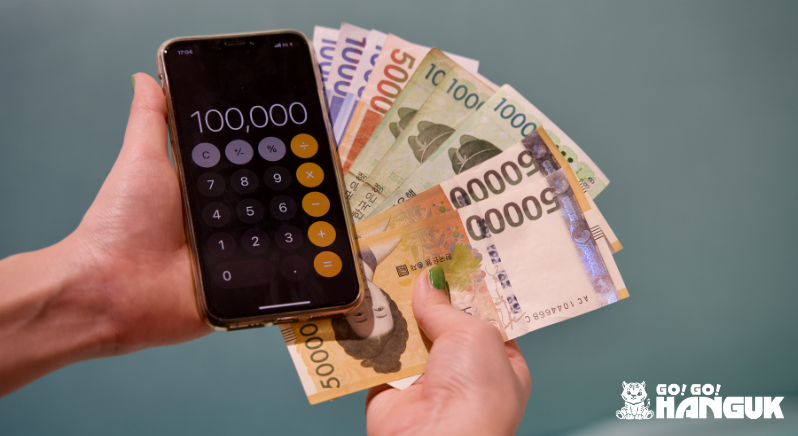 Person holding Korean won bills and a calculator