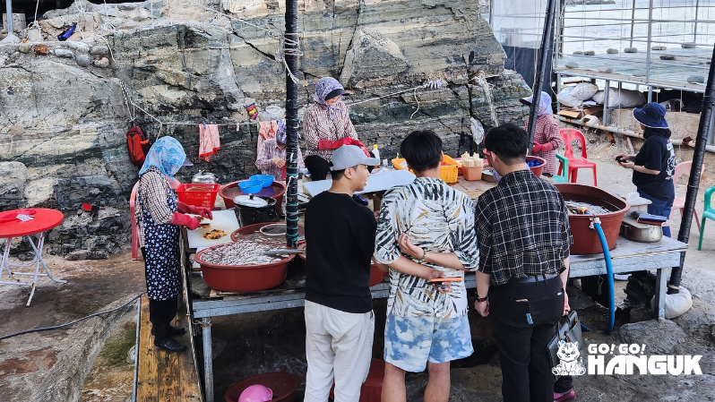 釜山の海沿いで海鮮を並べる屋台と地元の人々